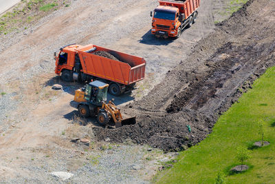 A worker on a tractor with a bucket loads earth into a truck.