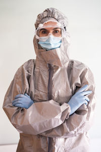 Portrait of woman wearing mask standing against white background