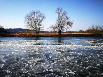 Scenic view of frozen lake against blue sky