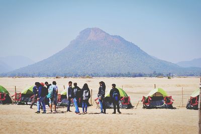 People at desert against mountain range
