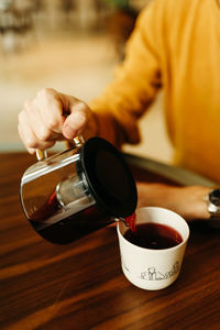 Close-up of hand holding coffee cup on table