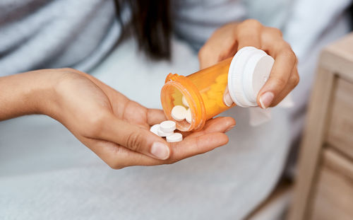 Midsection of woman holding pills