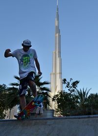 Low angle view of man with arms outstretched against clear sky