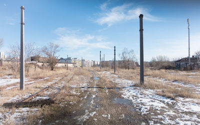 Bare trees by railroad tracks against sky during winter