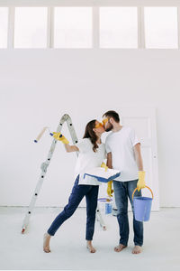 Happy smiling married couple engaged in renovation repair in the room of the house preparing to move