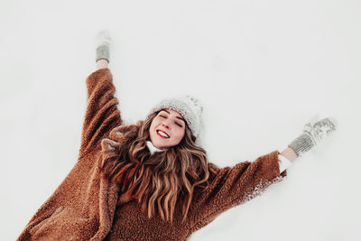 Young beautiful woman laying down on the white snow in the winter forest. girl is happy, closed eyes