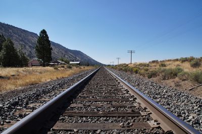 Railroad track by mountain against clear sky