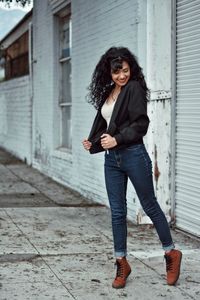 Portrait of smiling young woman standing against wall