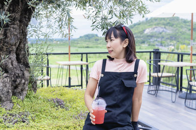 Happy asian woman smiling and showing ice berry juice in a plastic cup refreshing drinks for summer 