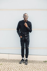 Portrait of young man standing in front of wall