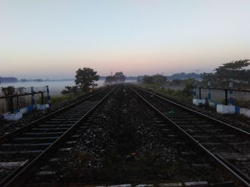 Railroad tracks against sky during sunset