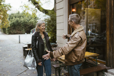 Man greeting woman arriving at date near restaurant