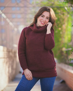 Happy young woman standing against blurred background