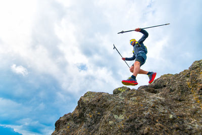 Male athlete falls over a cliff with sticks while practical training at the mountain trail