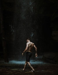 Full length of shirtless man running in forest