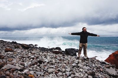 Man standing on beach against cloudy sky