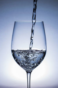 Close-up of wineglass on glass against white background