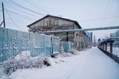 Snow covered houses by building against clear sky