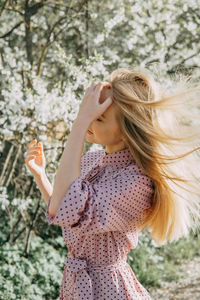 Blonde girl on a spring walk in the garden with cherry blossoms. female portrait, close-up. 