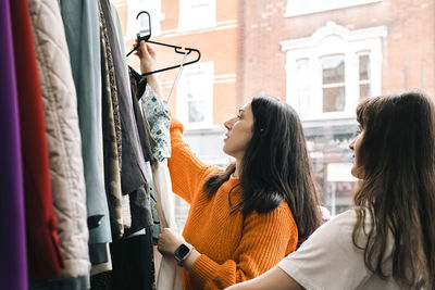 Young friends examining clothes in clothing store