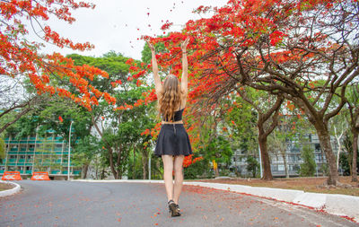 Rear view of woman walking in park with red flowers