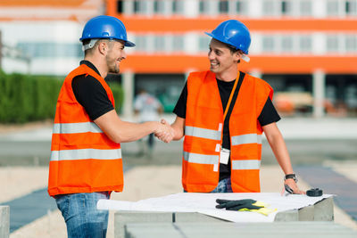 Engineers shaking hands over blueprint at construction site