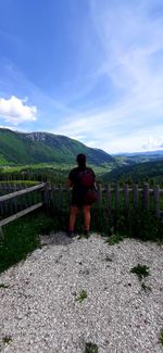 Rear view of woman standing on mountain against sky