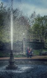 Water splashing on fountain against trees during rainy season