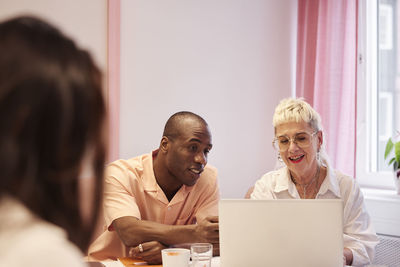 Coworkers sitting at business meeting and using laptop