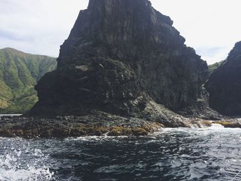 Scenic view of sea by mountain against sky