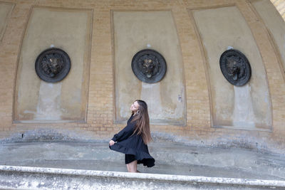 Full length of woman standing against building