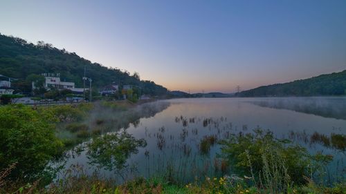 Scenic view of lake against clear sky during sunset