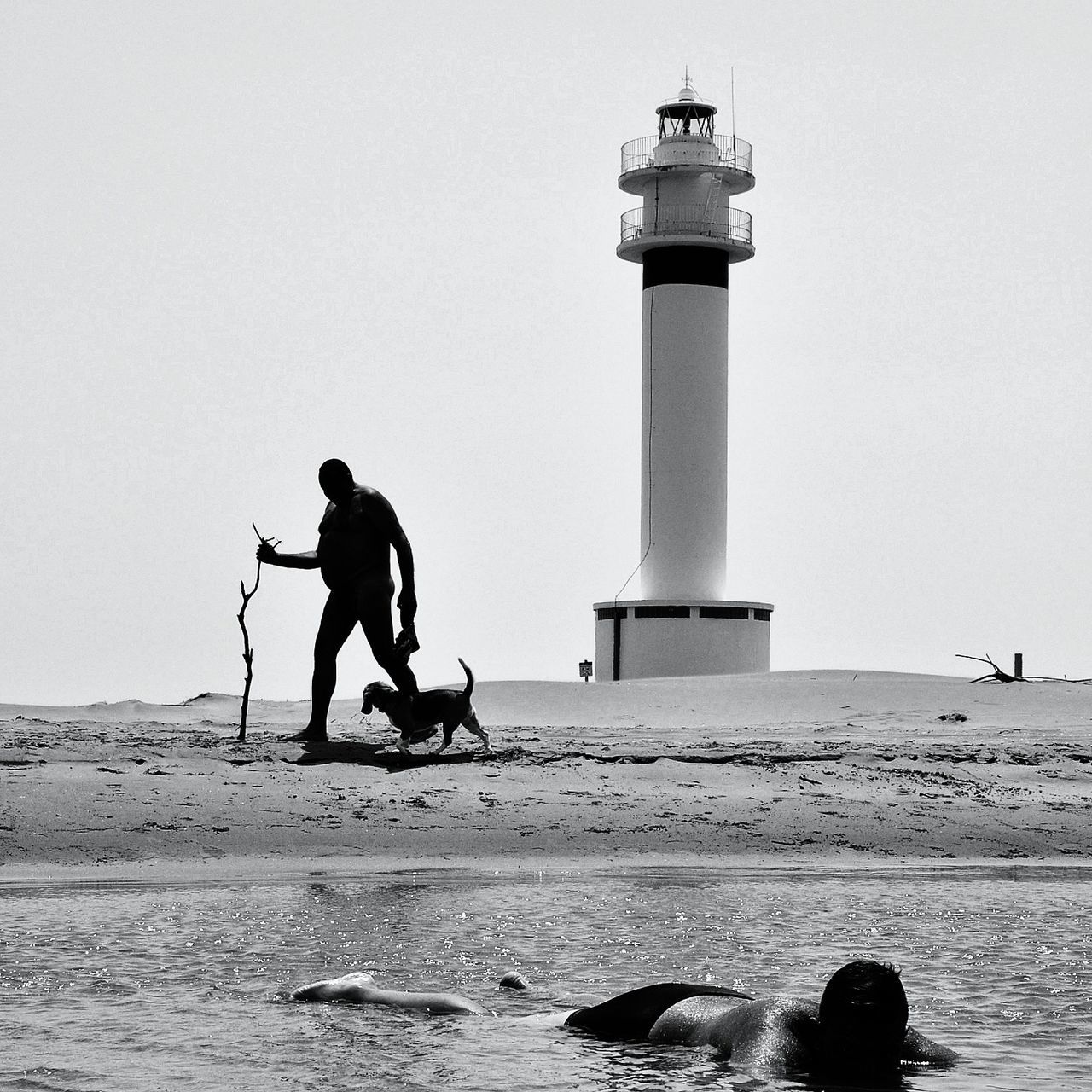 sea, clear sky, water, men, lifestyles, leisure activity, beach, full length, lighthouse, built structure, copy space, shore, person, vacations, rear view, architecture