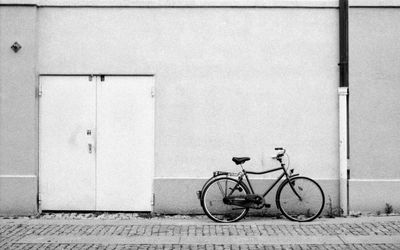 Bicycle parked on footpath against wall