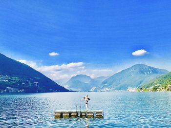 Man standing on lake against blue sky