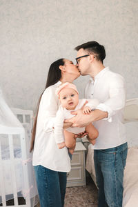 Happy mother and daughter standing against wall