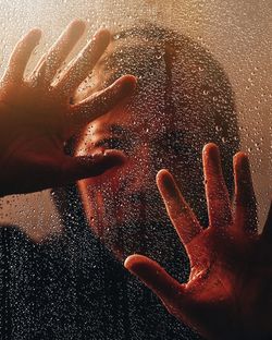 Close-up of wet hand touching glass window