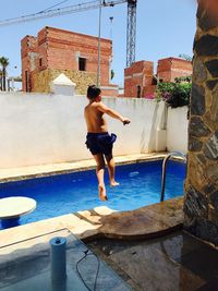 Full length of shirtless boy jumping into swimming pool