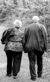 Rear view of senior couple walking on footpath