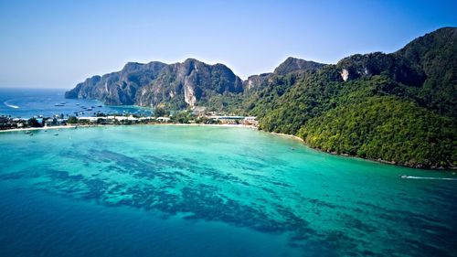 Scenic view of sea and mountains against clear blue sky