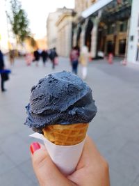 Midsection of person holding ice cream cone on street