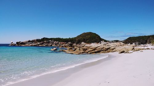 Scenic view of beach against clear blue sky