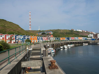 Pier over river by buildings in city against sky