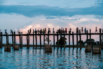 People standing by lake against sky