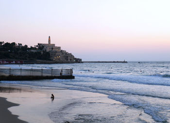 Sunset over beach of tel aviv-jaffa with jaffa's skyline in the background.