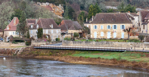 Houses by river against buildings