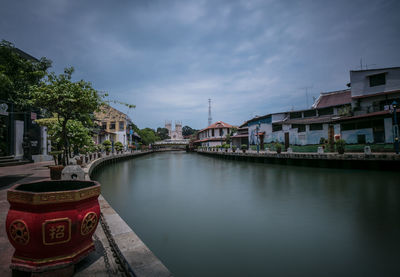 Bridge over river by buildings in city against sky