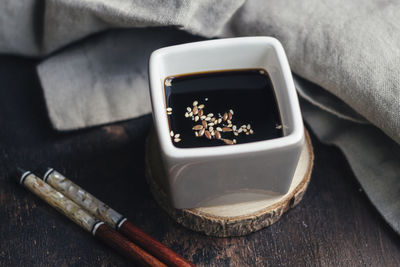 Vessel with soy sauce and sesame on a wood slice