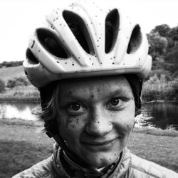 Portrait of young woman wearing cycling helmet against lake