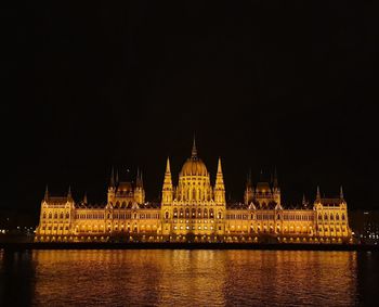 View of illuminated building by river at night